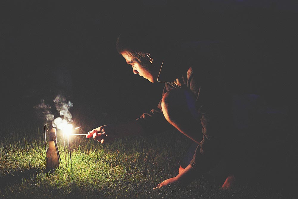Young man using a punk to light fireworks.